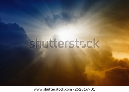 Religious background - bright sunlight from dark red and blue sky, rays of hope