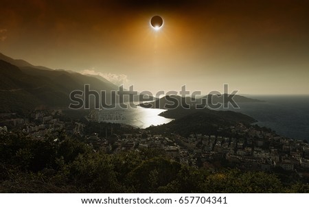 Amazing scientific background - total solar eclipse in dark red glowing sky above seaside city, mysterious natural phenomenon when Moon passes between planet Earth and Sun.