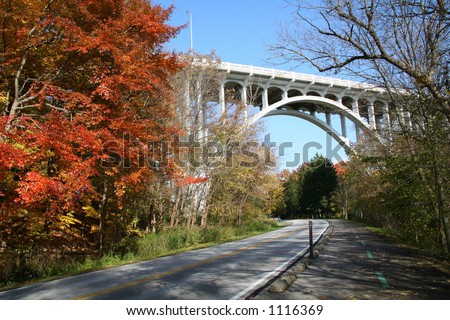 White bridge in park flanked by beautiful autumn foliage.