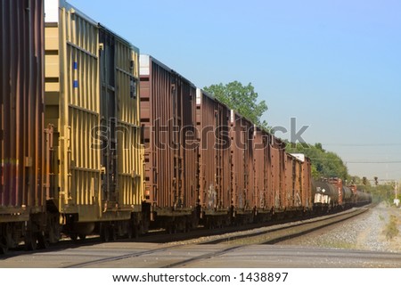 Freight train pulling several box and tank cars on a summer day.