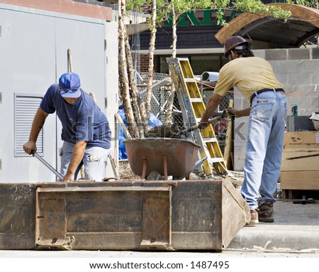 Two brick layers shoveling mortar concrete and setting up bricks on a construction site.