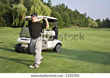 Man in front of golf cart on fairway - follow-thru swing.