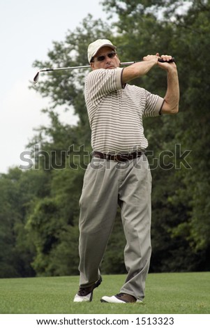 Male golfer completes swing.