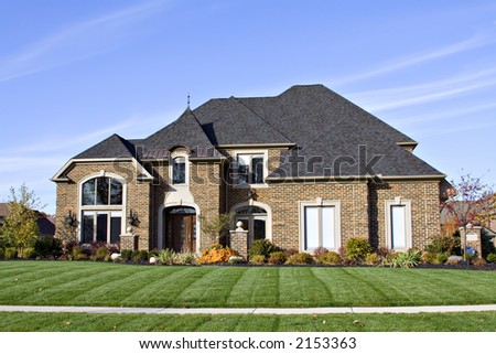 A large American brick home with many roof angles and windows.