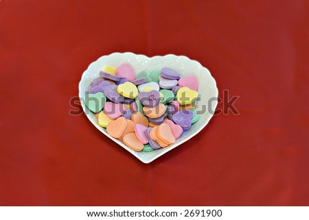 Heart shaped dish of conversation hearts.  I love you on top.