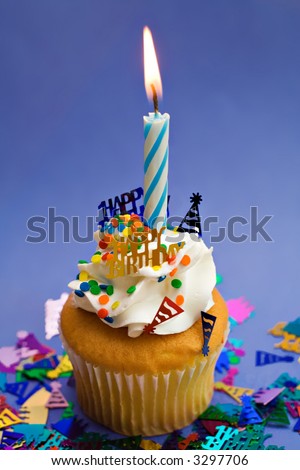 A blue birthday theme party cupcake with lit candle.