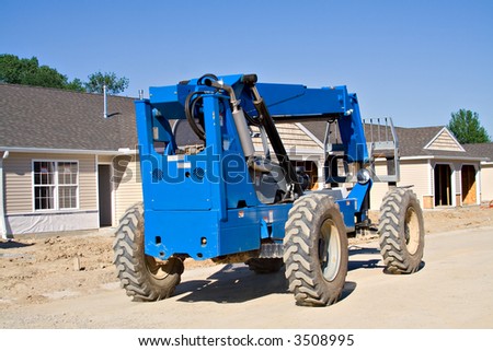 A new row-housing development in the process of being built.  Blue forklift tractor.