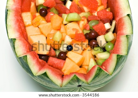 A carved watermelon basket of fresh fruits.