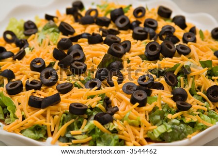 A dish of layered taco bean dip set out for a party.