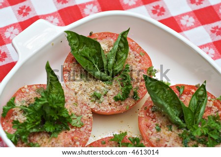 A baking dish of tomatoes prepared with herbs and spices for baking.