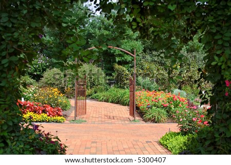 A private flower  garden complete with paths and iron gate - framed by vine covered entrance.