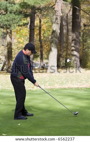 A male golfer plays a game on a beautiful fall day.
