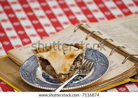 A piece of homemade apple pie - vintage plate and actual recipe book used to make the pie.