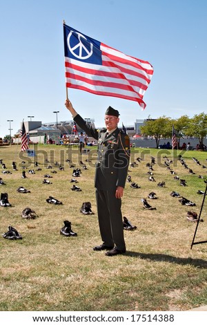 A Vietnam War Veteran waving a peace flag in front of a memorial for Ohio military killed in Iraq.  Cleveland Ohio on Labor Day 2008.
