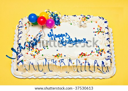 Large decorated Birthday cake with white icing, sprinkles, ribbons, balloons.