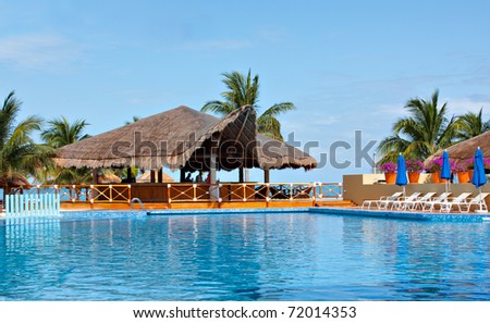 Cancun swimming pool and palapa overlooks ocean.