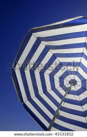 blue and white striped beach umbrella under clear blue sky