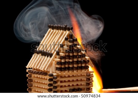 House build from matches on fire with black isolated background