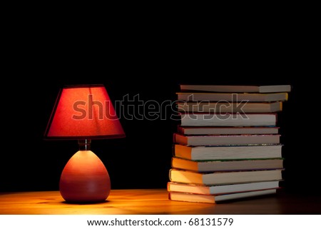 Lamp illuminating books on wooden table