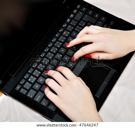 Close-up of female fingers typing a document on the black laptop