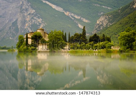 The Medieval Castle Toblino reflecting in the calm waters of Toblino Lake. Trentino, Italy