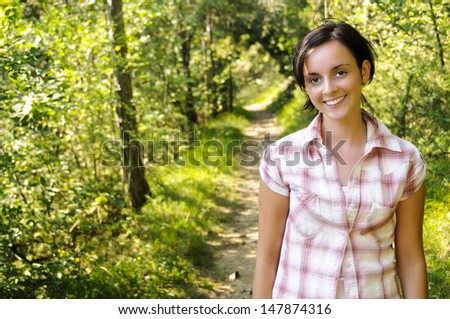 A smiling young Caucasian girl wearing mountain clothes on a hiking path in the wood