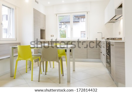 Modern kitchen interior with wooden cabinets, white table, grey and yellow chairs