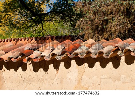 Traditional terra cotta tiles top an adobe wall in Santa Fe, New Mexico