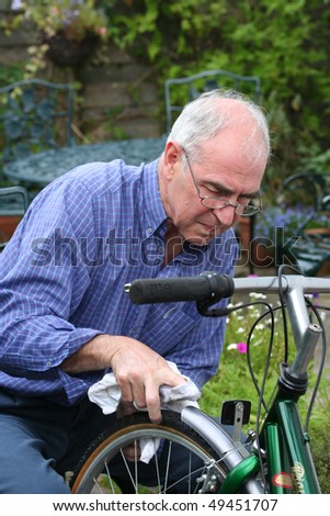 Senior man cleaning bicycle in close up