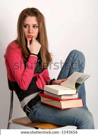 Pretty college-age woman looking off as she studies with a pile of books in her lap. College-age woman balancing books on her head.
