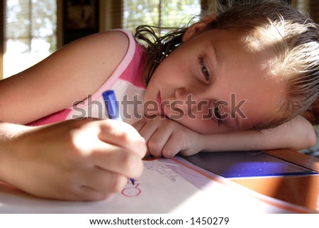 Young girl leaning her head down as she colors on a piece of paper.