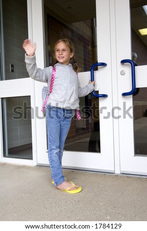 Young grade school age girl waves as she heads off to school