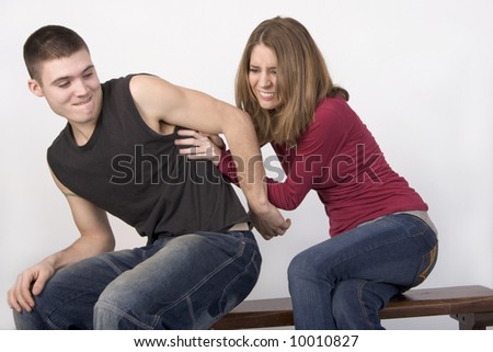 Young couple sitting on a bench wrestling