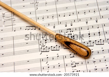 A natural wood conductors baton on an orchestral score.
