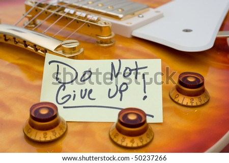 A guitar with a note on reminding the player to not give up.