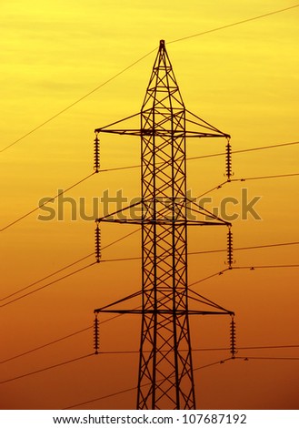 A image showing a pole used for distribution high tension  cables of electricity with good golden sky background.