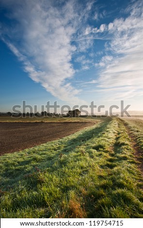 Landscape in Autumn Fall across foggy and icy fields towards sunrise