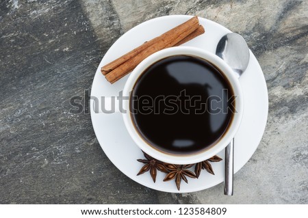 Birds eye view of hot coffee on slate background with cinnamon sticks and star anise