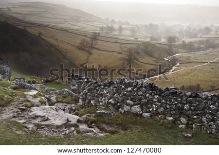 View of misty Malham Dales from limestone pavement above Malham Cove in Yorkshire Dales National Park