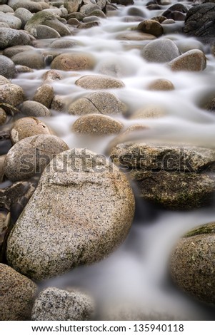 Stream flows over water worn round rocks