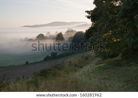 Foggy Autumn landscape over agricultural fields with layers of fog