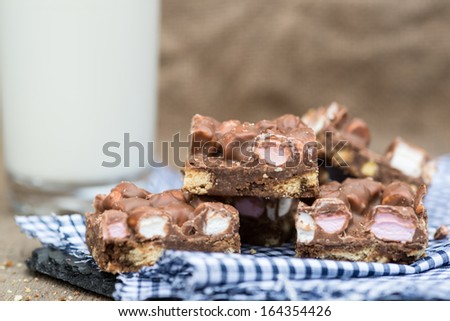 Rocky road squares on rustic background with glass of milk