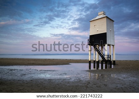Wooden stilt lighthouse on sandy beach at sunrise landscape