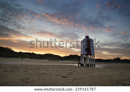 Wooden stilt lighthouse on sandy beach at sunrise landscape