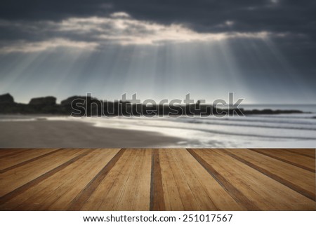 Stunning sun beams bursting from sky over empty yellow sand beach landscape with wooden planks floor