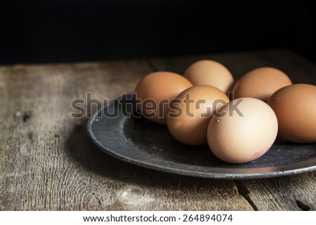 Fresh eggs on pewter plate in vintage style natural lighting set up