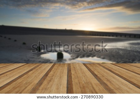 Beautiful sunrise reflected in low tide water pools on beach landscape with wooden planks floor