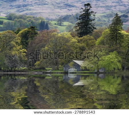 Forest landscape reflected in calm water of Consiton Water in Lake District