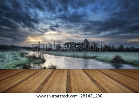 Beautiful dawn landscape of Priory ruins in countryside location with wooden planks floor