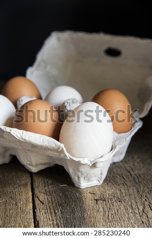 Fresh eggs in egg box in moody natural lighting vintage style set up